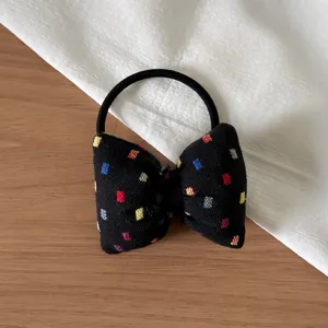 Chic black bow hair tie with colorful squares pattern, ideal for high ponytails and DIY.