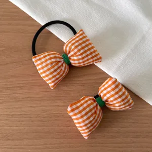 Détail de chouchou en tissu à carreaux orange et blanc, accessoire de cheveux mignon.