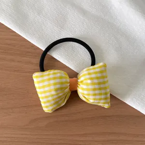 Détail d'élastique à cheveux nœud à carreaux jaunes, accessoire pour queues de cheval mignonnes.