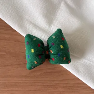 Detailed view of a charming green fabric bow accessory with colorful square patterns.