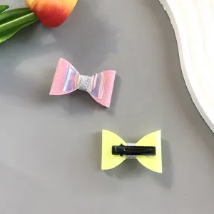 Close-up detail of cute glitter bow hair clips, pink and yellow variants with laser finish.