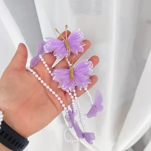 Gros plan détaillé de pinces à cheveux papillon en résille violette avec chaînes de perles.