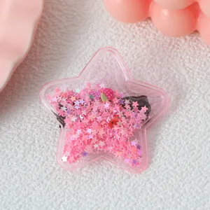 Gros plan détaillé d'une jolie pince à cheveux étoile à paillettes roses et breloques.