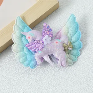 Detailed close-up of glittering unicorn hair clip with angel wings, sparkling sequins and bow.