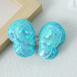 Primo piano di una molletta per capelli a farfalla con paillettes azzurre e finitura lucida.