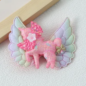 Close-up detail of a cute pink unicorn hair clip with iridescent angel wings for kids.