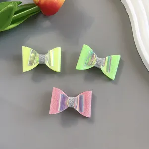 Close-up detail of cute handmade bow hair clips with holographic and glitter elements.