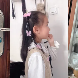 Vue détail de pince à cheveux tressée avec chaîne de perles et papillon rose d'enfants.