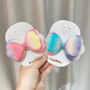 Primo piano di fermagli per capelli con fiocco glitterato sfumato a doppio strato, colorato e lucido.