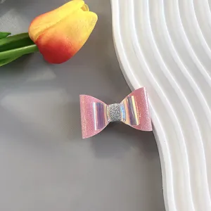 Close-up view of pink glitter bow hair clip detail, sweet decorative kids hair accessory.