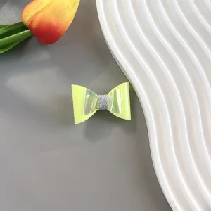 Close-up detail of a handmade neon yellow bow hair clip with holographic laser wings and glitter.