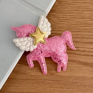 Pink glitter unicorn patch detail with white angel wings and gold star for DIY hair accessories.