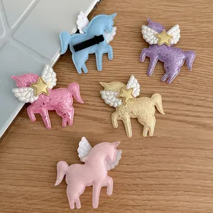 Close-up detail of colorful glitter unicorn hair clips with angel wings for kids styling.