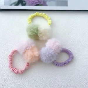 Close-up detail of colorful furry pom-pom hair scrunchies, soft plush elastic ties for cute girls.