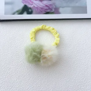 Detailed close-up of fluffy pom-pom hair tie with yellow elastic band, sweet and cute design.