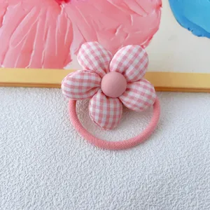 Pink gingham fabric flower hair tie detail close up, cute floral hair scrunchie accessory.