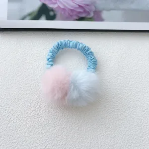 Close-up of cute children color-block furry pom-pom hair tie on white texture background.