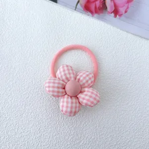 Close-up of a cute pink plaid fabric flower hair tie, showcasing the delicate bow and elastic band.