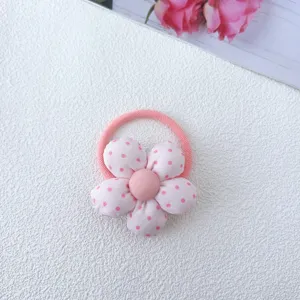 Close-up of pink polka dot fabric flower hair tie, cute floral design for children and girls.