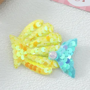 Gros plan détaillé d'une pince à cheveux queue de sirène en sequins colorés avec perle.
