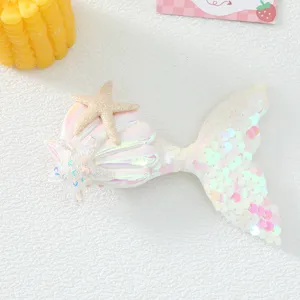 Close up detail of mermaid tail hair clip, featuring sparkly sequins and cute seashell design.