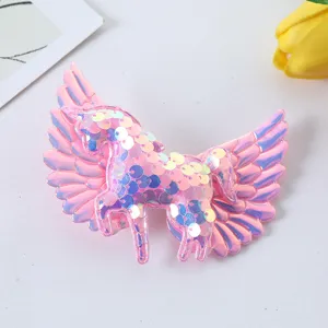 Close-up view of pink sequin unicorn wings hair clip, highlighting sparkling glitter details.