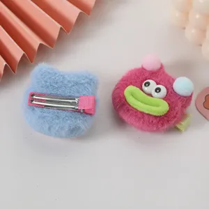 Jolie pince à cheveux en peluche avec design de monstre drôle, gros plan sur la texture douce.