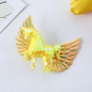Detailed close-up of yellow sequin unicorn wing hair clip showing sparkling texture.