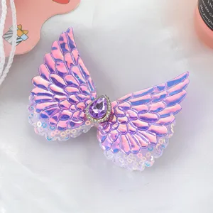 Detailed close-up of cute pink angel wing hair clip with sparkly purple rhinestone.