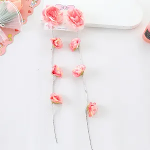 Detalle de pinza de pelo con cadena de cristal trenzada de flores rosas y borla larga para niña