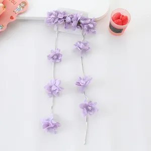 Vista detallada de la cadena con borla de pelo floral morado, flores de tela fina y brillante.