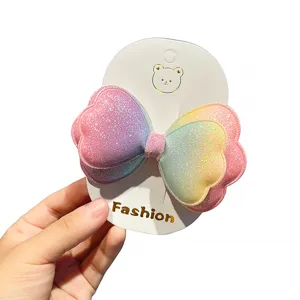Primo piano del fermaglio per capelli con fiocco a cuore sfumato glitterato su cartoncino.