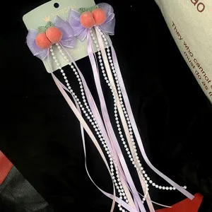 Delizioso fermaglio per capelli con fiocco di pesca e lunghe nappe di perle, dettaglio fine.