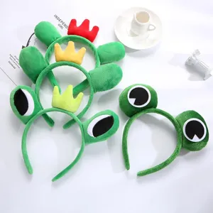 Detalles en primer plano de bonitas diademas de felpa verde con ojos de rana y corona.