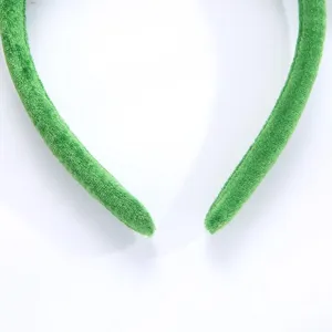 Detalle de diadema de terciopelo verde, banda de pelo de felpa suave, accesorio cómodo.