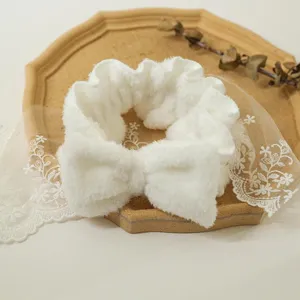 Primo piano dettaglio del cerchietto con fiocco in peluche bianco, morbida consistenza.