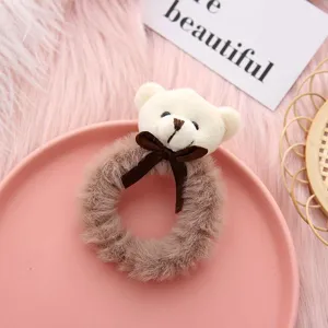Close-up detail of a cute plush bear hair scrunchie with bow, soft furry texture design.
