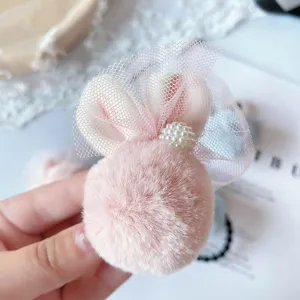 Détail chouchou cheveux oreilles de lapin en peluche rose avec nœud filet et perle.