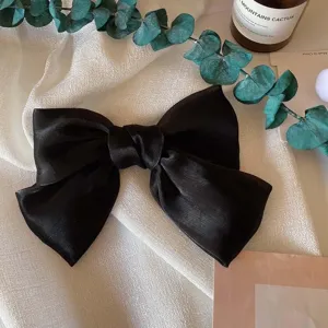 Dettaglio molletta per capelli fiocco raso nero francese, elegante sfondo stoffa.
