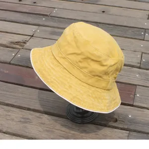 Detail view of washed distressed yellow bucket hat with white trim for casual wear.