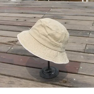 Close-up detail of a classic khaki washed cotton bucket hat with breathable metal eyelets.