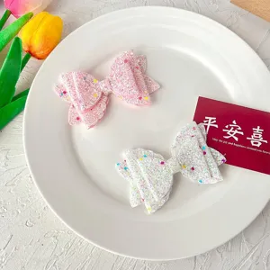 Detailed view of sparkly glitter bow hair clips for kids, cute pink and white hairpins.
