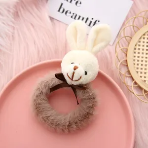 Cute plush animal hair tie detail, fluffy brown hair ring with sweet bow decoration closeup.