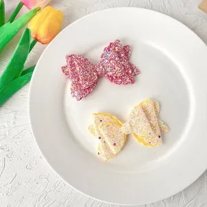 Glitter bow hair clips for kids, sparkly pink and yellow hairpins, cute hair accessories.