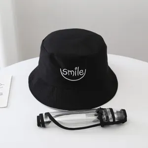 Detachable face shield bucket hat detail showing black cotton hat with smile embroidery.