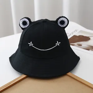 Cute black cotton bucket hat with frog eyes and white embroidered smile for outdoor travel.