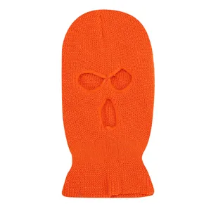 Close-up detail view of bright orange knitted three-hole ski mask, windproof winter thermal gear.