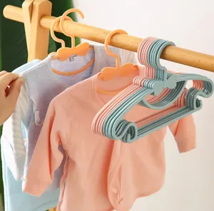 Close up detail of cute baby clothes plastic hangers with bow design in use on wooden rack.