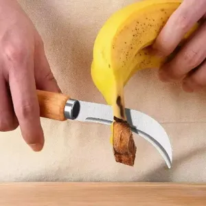 Detailed view of stainless steel fruit utility knife with wooden handle cutting banana tip.