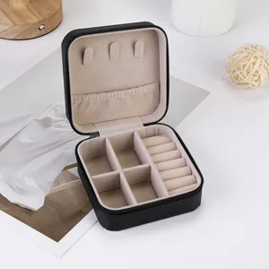Portable black travel jewelry box with multiple compartments, ring rolls and necklace hooks for safe storage.